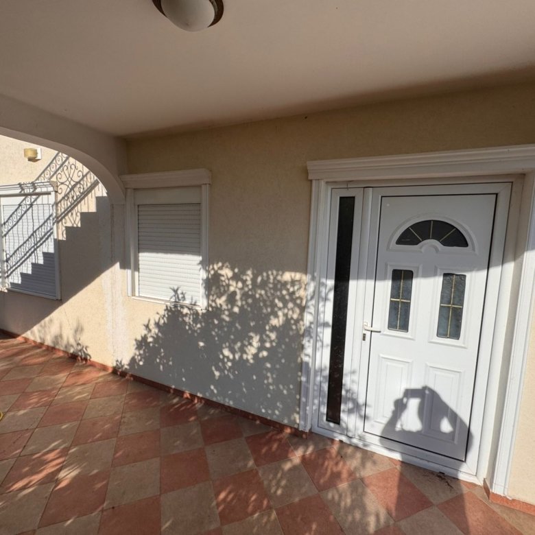 Modern white front door with glass panel and tiled entry, ideal Ulcinj real estate by ekosphere doo via immorenta.me.