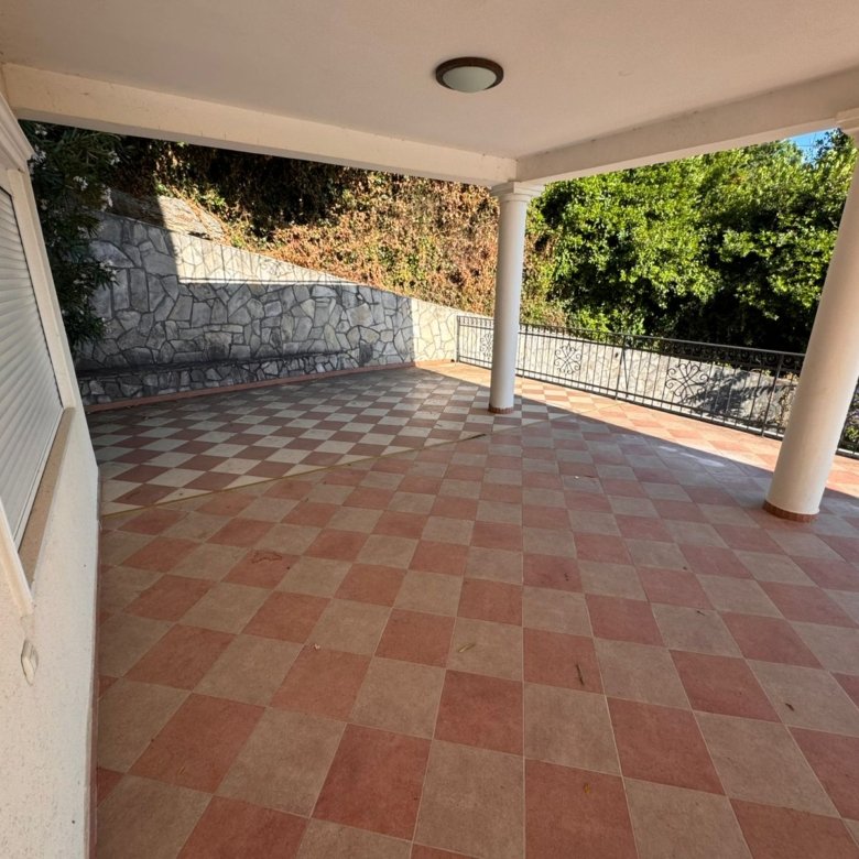 Elegant covered patio in Ulcinj, Montenegro with checkered tile, white columns, and lush greenery. Exclusive by immorenta.me (Ekosphere).
