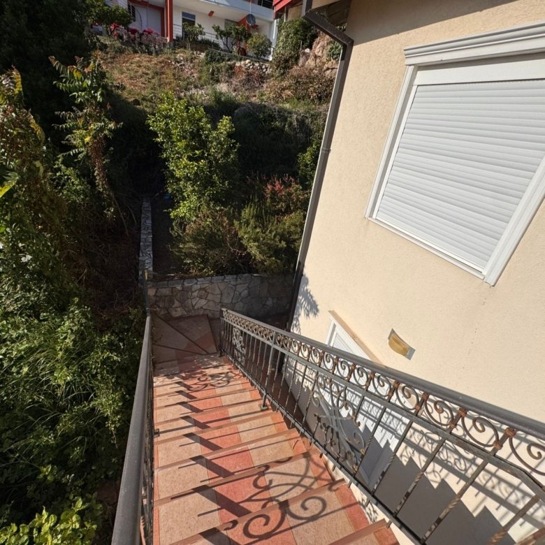 Elegant terracotta-tiled staircase with black railing and lush greenery, a prime Ulcinj real estate feature&mdash;immorenta.me by ekosphere doo.