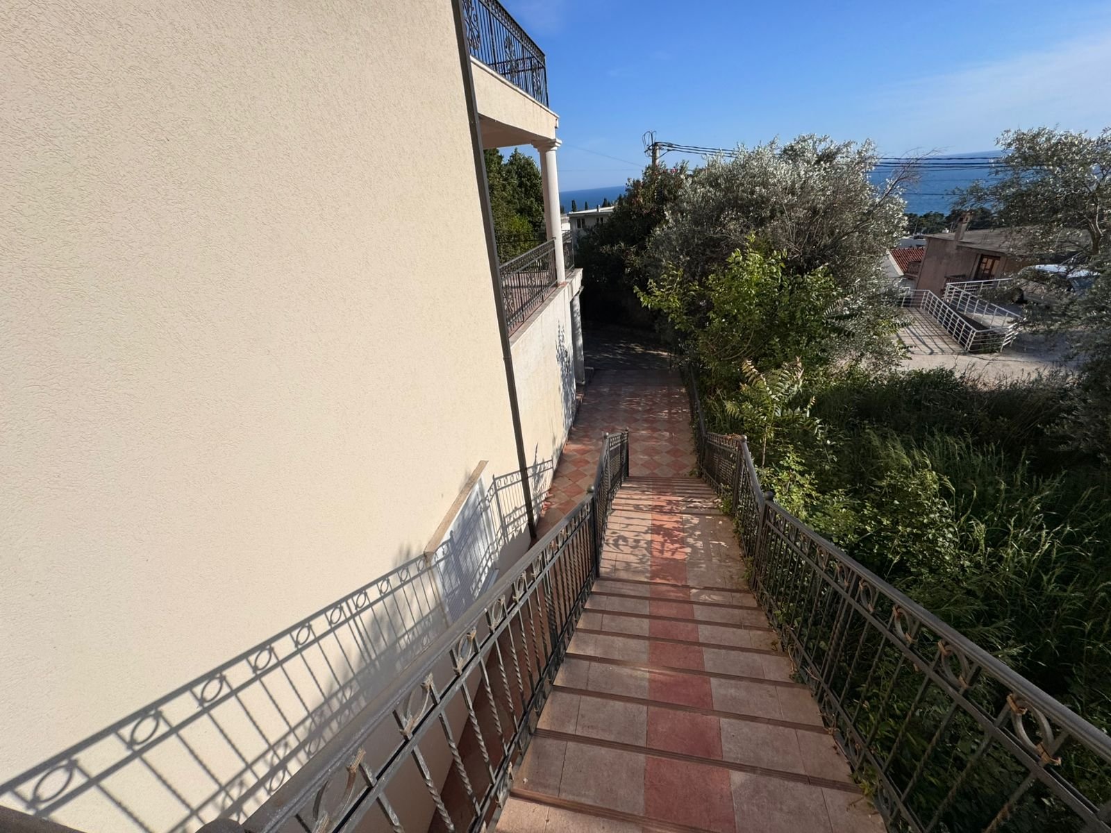Modern sloped walkway with metal railing by a stylish building, lush greenery, sea views&mdash;prime Ulcinj investment. Eksophere doo project.