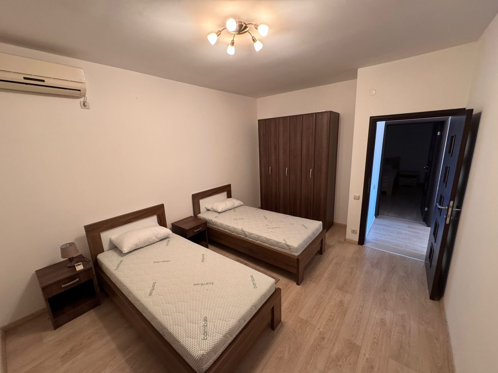 Modern Ulcinj bedroom with two single beds, wood flooring, AC, wardrobe&mdash;ideal Montenegro investment via immorenta.me.
