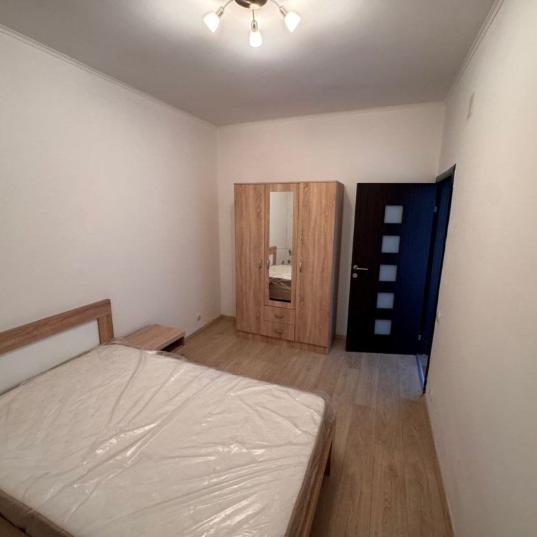 Modern Ulcinj bedroom with wooden bed, mirrored wardrobe, and sleek flooring&mdash;prime investment at immorenta.me by Ekosphere DOO.