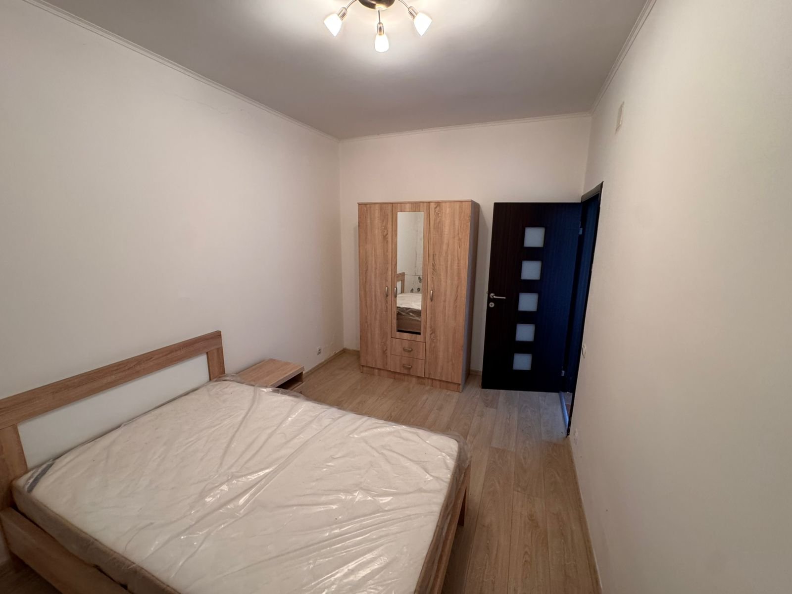 Modern Ulcinj bedroom with wooden bed, mirrored wardrobe, and sleek flooring&mdash;prime investment at immorenta.me by Ekosphere DOO.