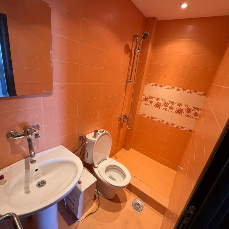 Modern Ulcinj bathroom with orange tiles, wall-mounted sink, walk-in shower&mdash;prime Montenegro property by Ekosphere, immorenta.me.
