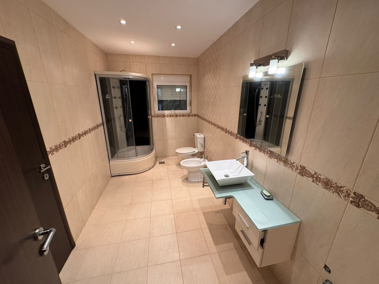Elegant Ulcinj bathroom: beige tiles, glass shower, premium fixtures&mdash;ideal property investment on immorenta.me by ekosphere doo.