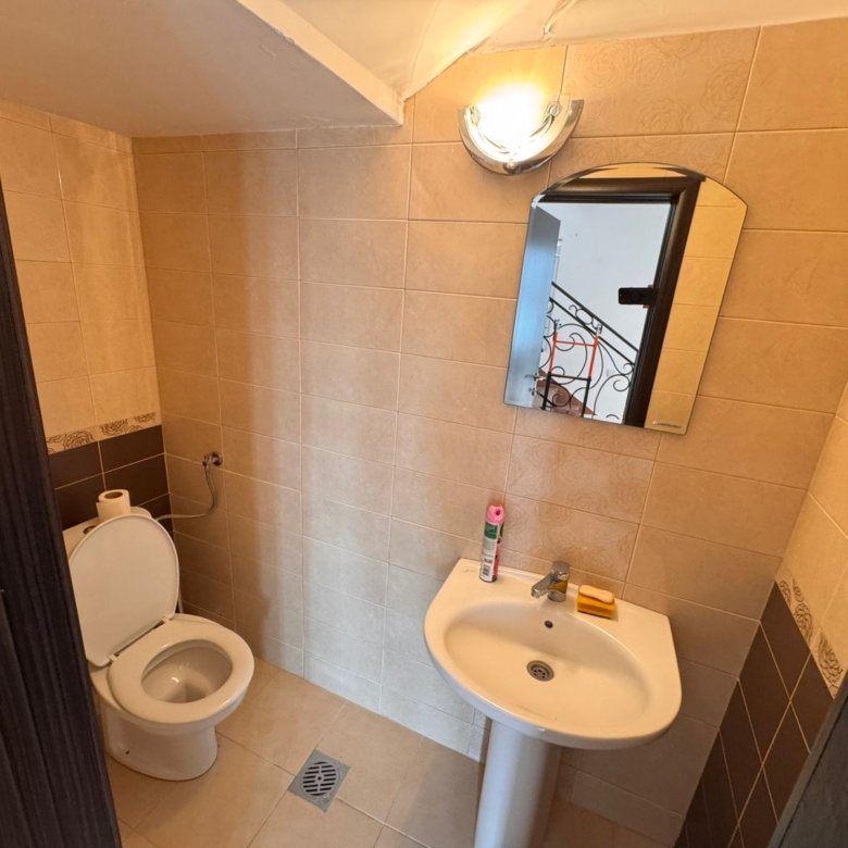 Modern bathroom in Ulcinj, Montenegro property&mdash;beige tiles, white fixtures, mirror with lighting. Exclusive listing on immorenta.me by ekosphere doo.