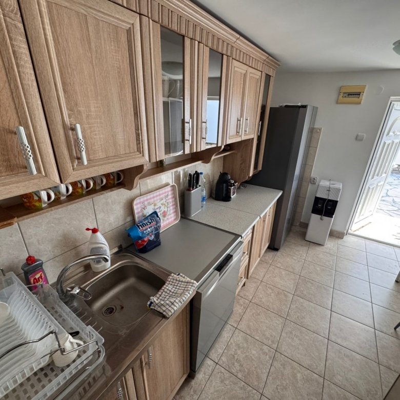 Sunlit kitchen with wooden cabinets, modern appliances, and patio access in Ulcinj&mdash;premium eco real estate by ekosphere at immorenta.me.