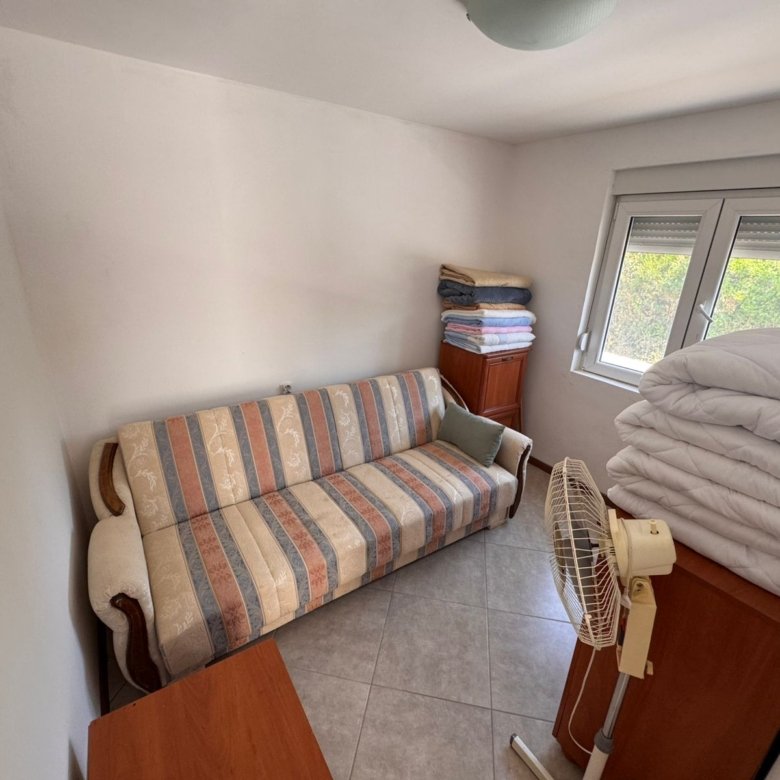 Discover a cozy, meticulously maintained Ulcinj property featuring a stylish striped sofa, desk, and storage; invest with immorenta.me by ekosphere doo.