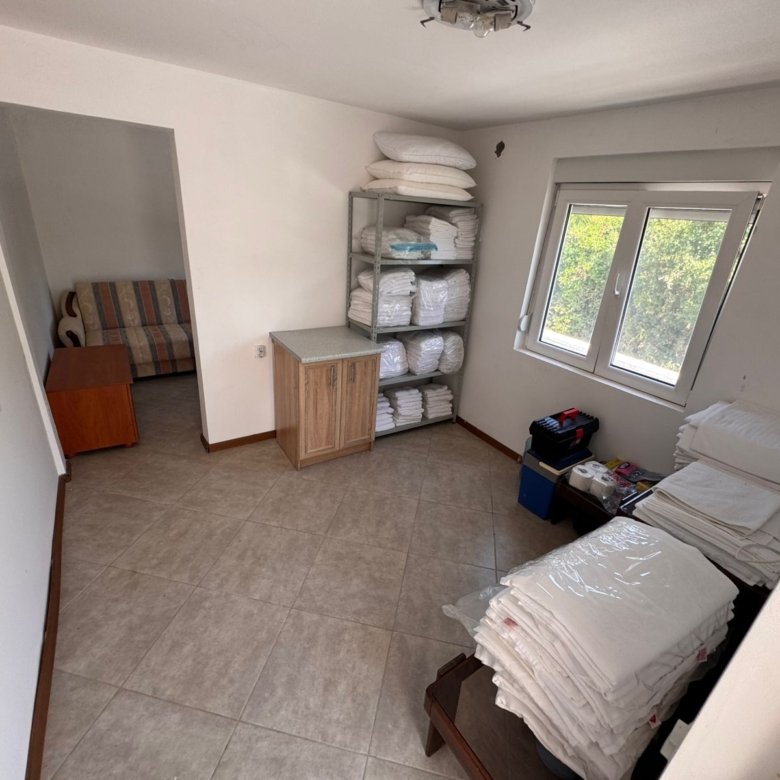 Modern tiled utility room in Ulcinj, Montenegro with organized storage, natural light, and adjoining lounge&mdash;exclusive at immorenta.me by ekosphere doo.