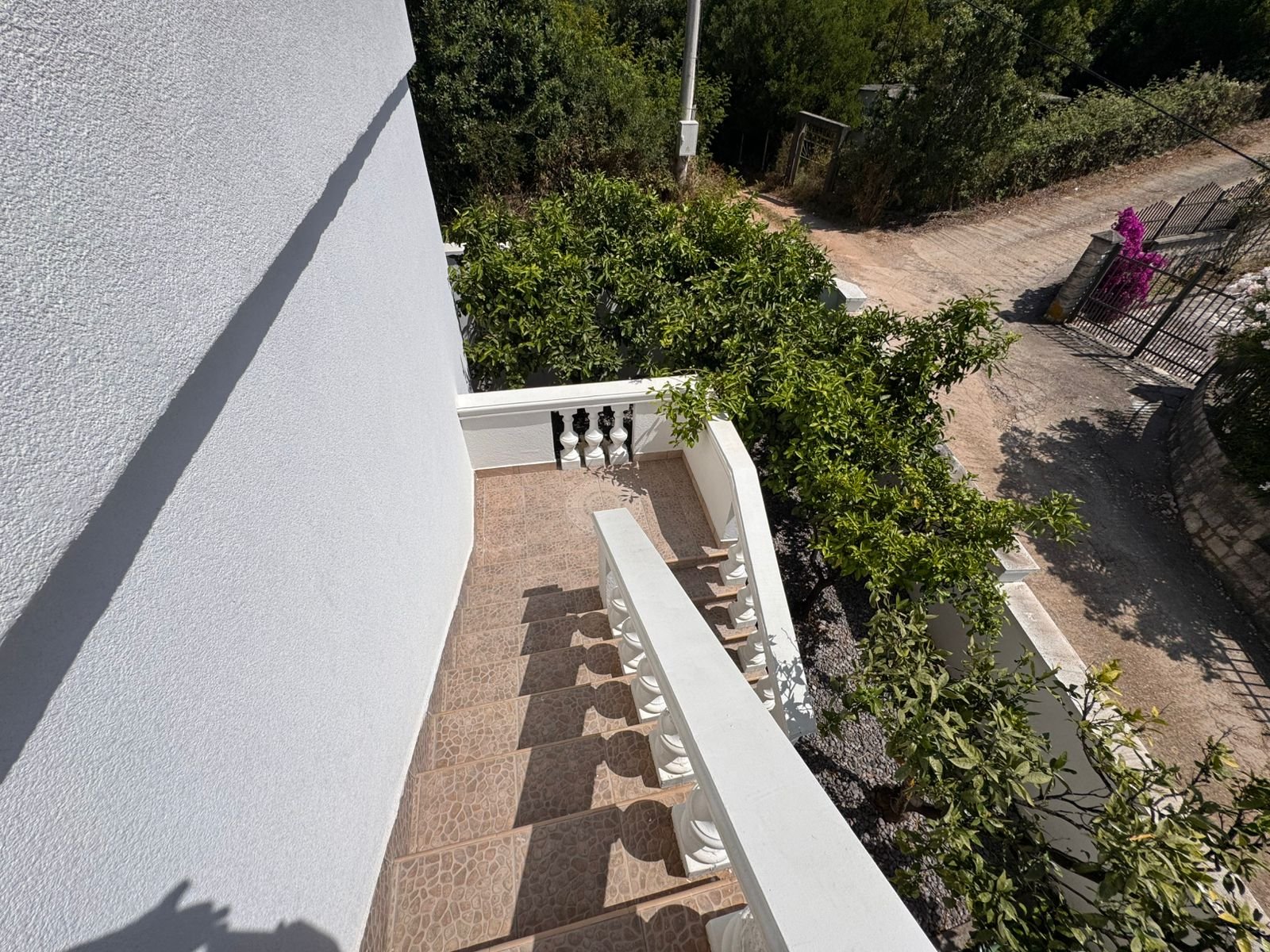 Modern outdoor staircase with white railings, brown tiles, and lush greenery&mdash;prime Ulcinj property via immorenta.me by Ekosphere.