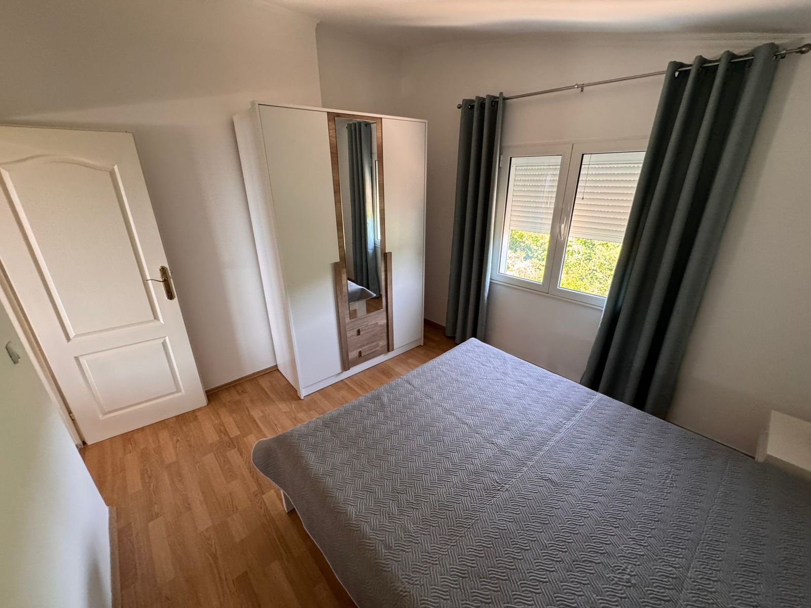 Stylish Ulcinj bedroom: wooden flooring, gray bed, mirrored wardrobe. Invest in prime Montenegro real estate by Ekosphere on immorenta.me.