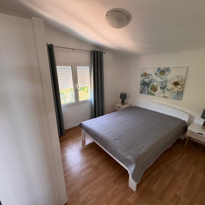 Elegant Ulcinj bedroom with hardwood floors, stylish bed, blue lamps; prime real estate&mdash;exclusively on immorenta.me by ekosphere doo.