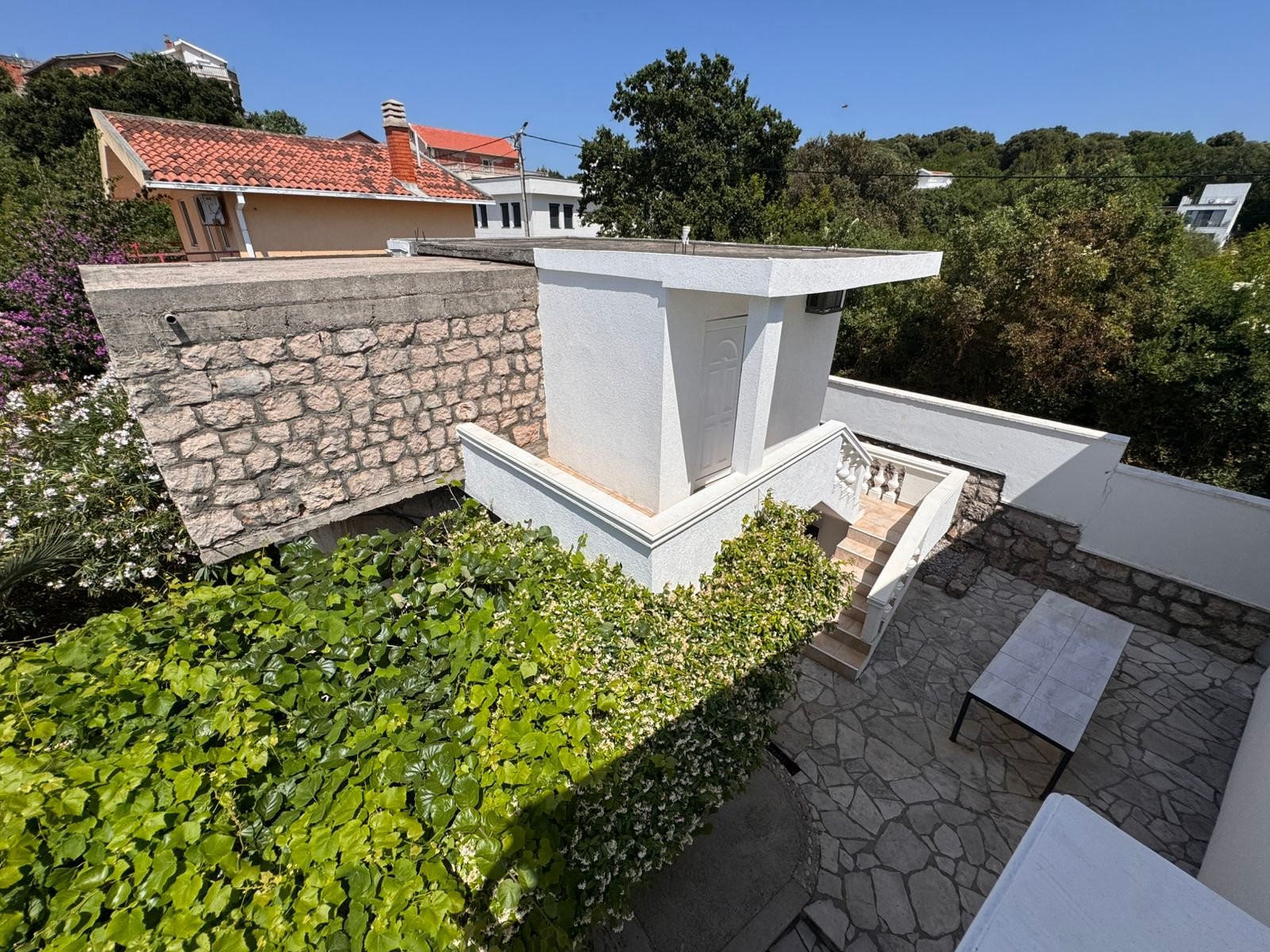 Charming white home in Ulcinj, Montenegro, with stone walls and lush greenery&mdash;ideal real estate investment at immorenta.me by ekosphere doo.