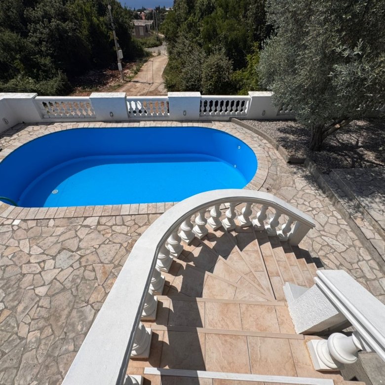 Elegant curved stone staircase with white railings to private pool, stone patio, and lush trees&mdash;prime Ulcinj real estate by ekosphere doo.