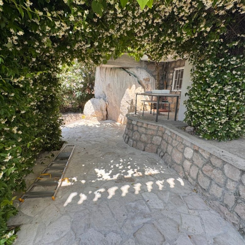 Elegant stone patio in Ulcinj, shaded by lush green archway. Ideal investment&mdash;exclusive at immorenta.me by Ekosphere doo.