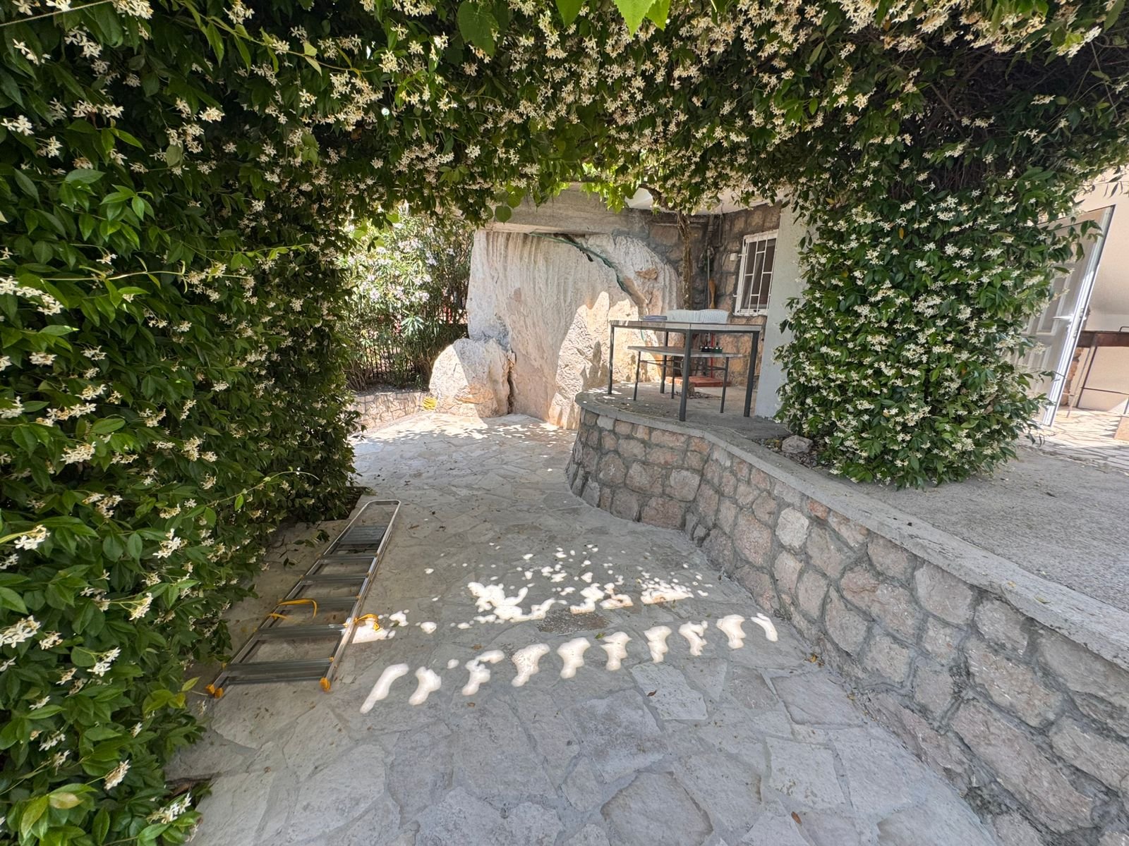 Elegant stone patio in Ulcinj, shaded by lush green archway. Ideal investment&mdash;exclusive at immorenta.me by Ekosphere doo.