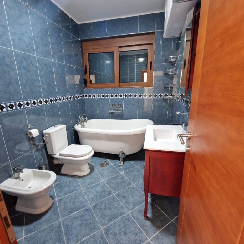 Modern bathroom in Ulcinj with blue tiles, freestanding tub, bidet, and window. Top Montenegro property by Ekosphere on immorenta.me.