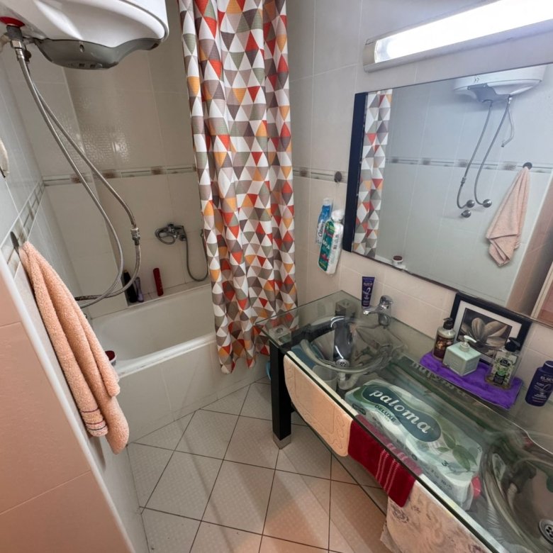 Modern Ulcinj bathroom with glass double sinks, tub, shower, plush towels; invest in Montenegro real estate with immorenta.me.