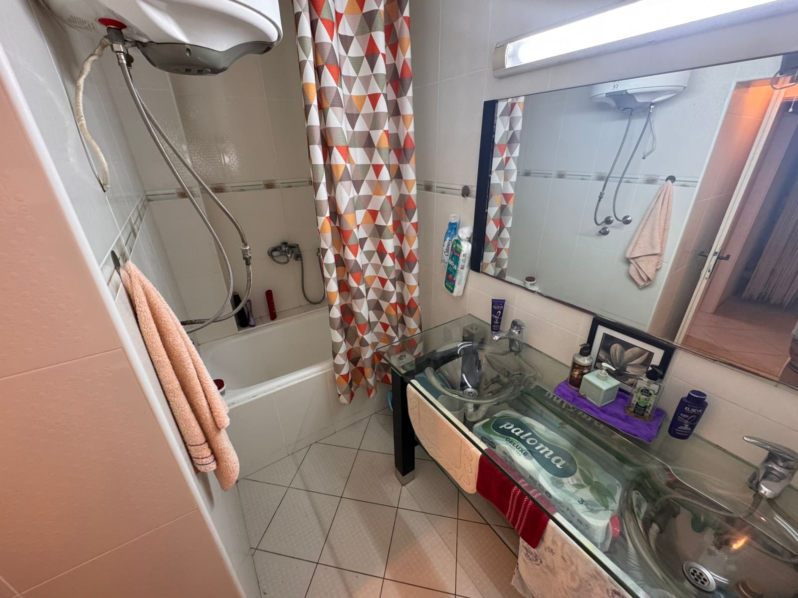 Modern Ulcinj bathroom with glass double sinks, tub, shower, plush towels; invest in Montenegro real estate with immorenta.me.