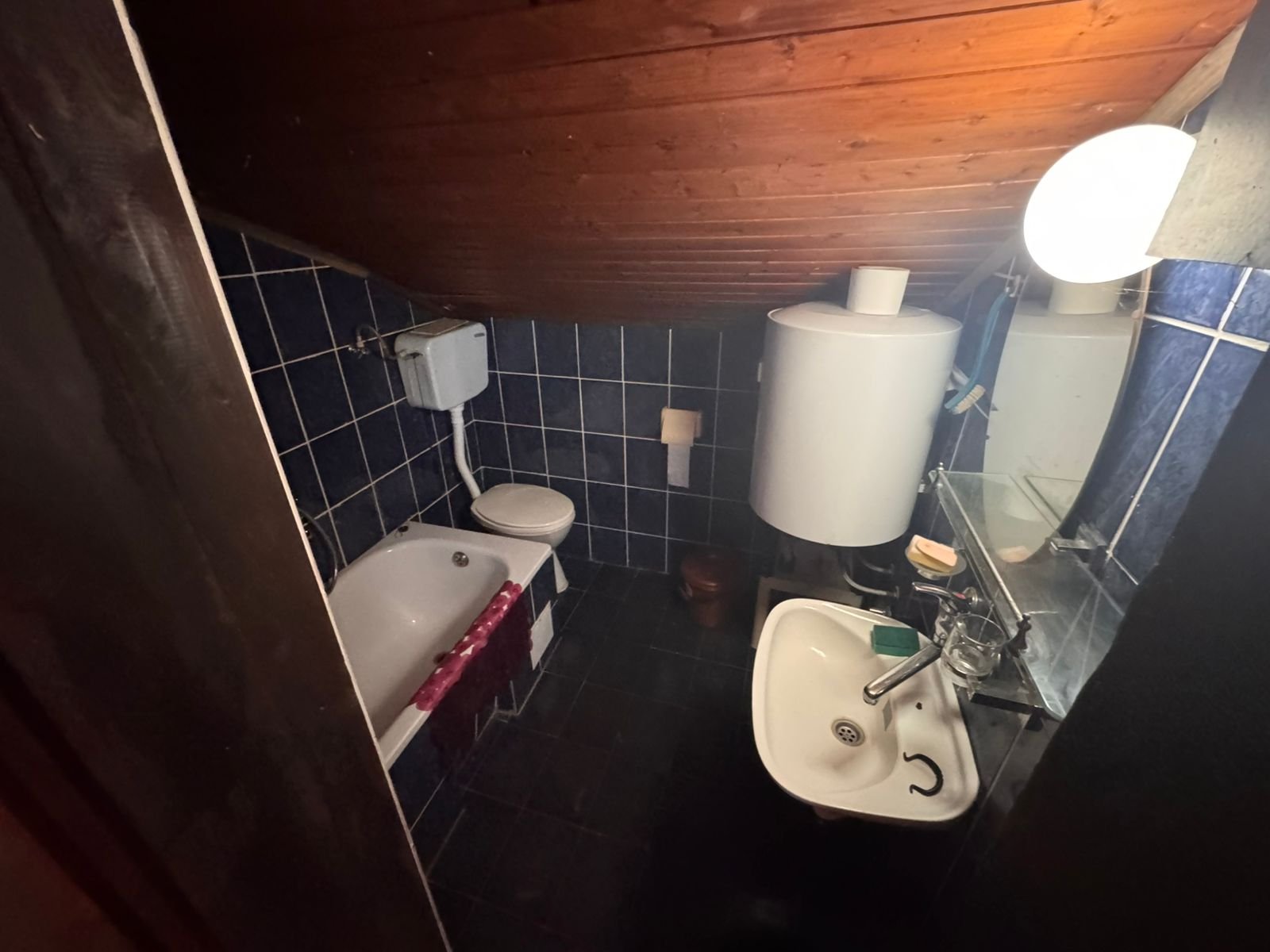 Modern bathroom in Ulcinj with blue tiles, wood-paneled ceiling, bathtub, and premium fixtures. Exclusive at immorenta.me/Ekosphere.