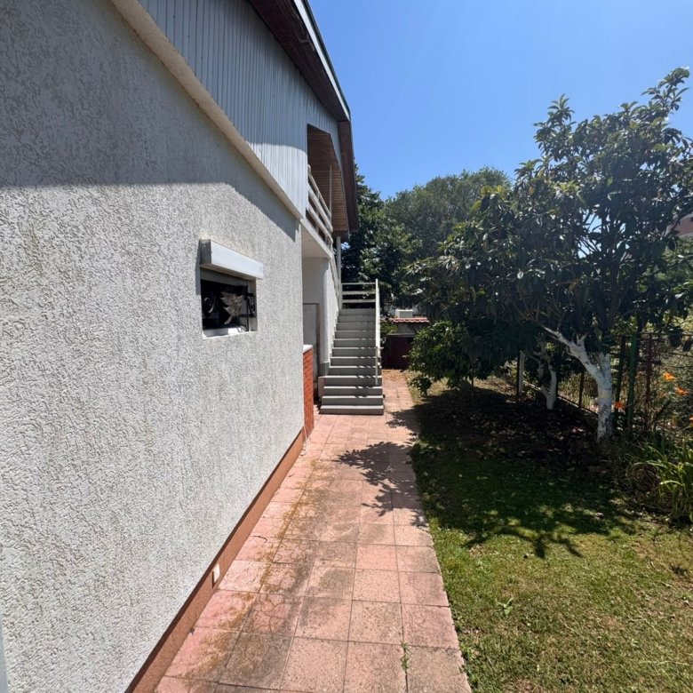 Stylish Ulcinj house with textured facade, lush garden, paved path, and stairs&mdash;ideal investment on immorenta.me by ekosphere doo.