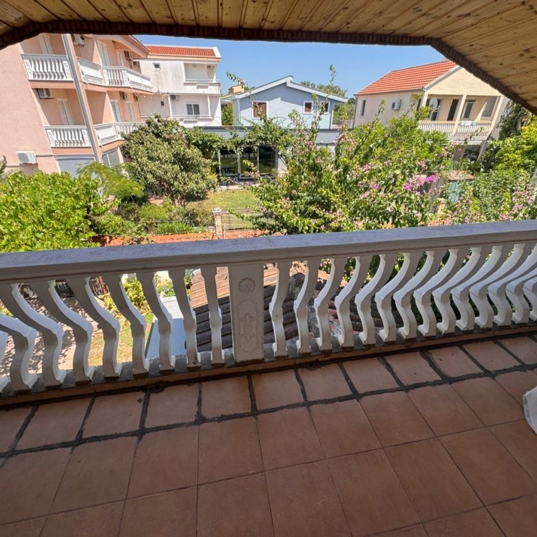 Spacious tiled balcony with white railing, garden view, and cityscape&mdash;prime Ulcinj property from immorenta.me by ekosphere doo.