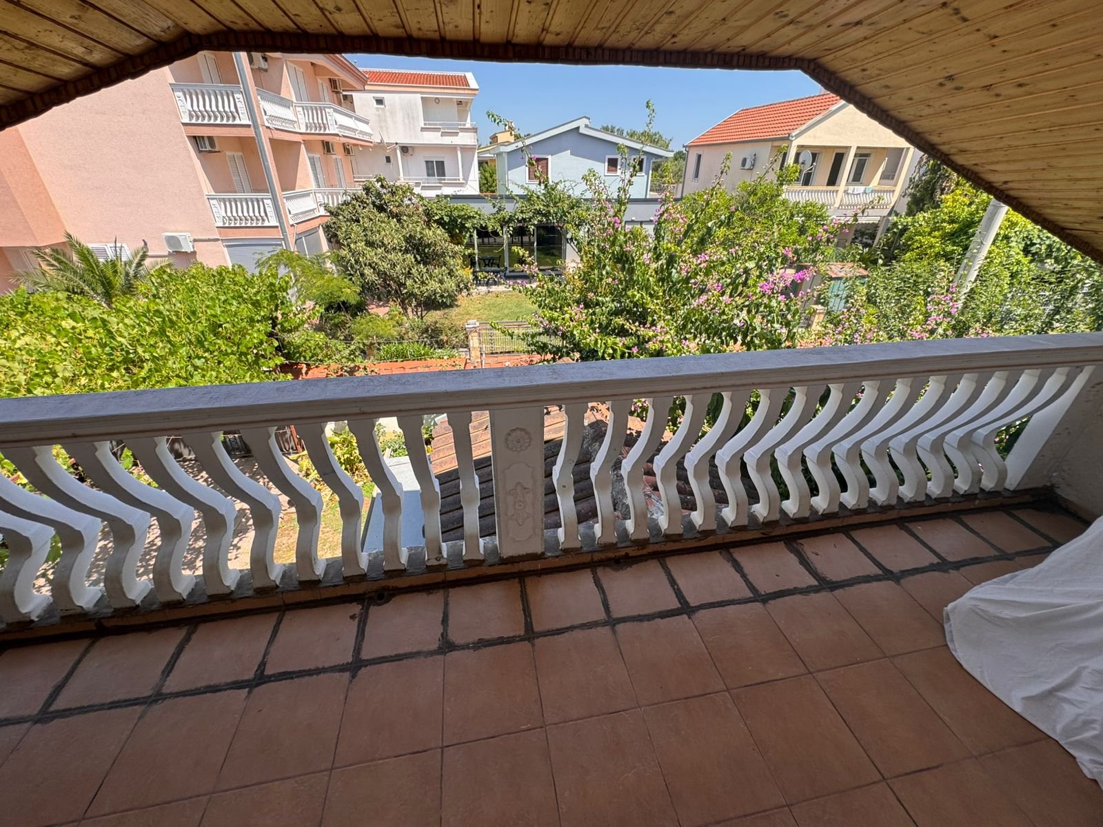 Spacious tiled balcony with white railing, garden view, and cityscape&mdash;prime Ulcinj property from immorenta.me by ekosphere doo.