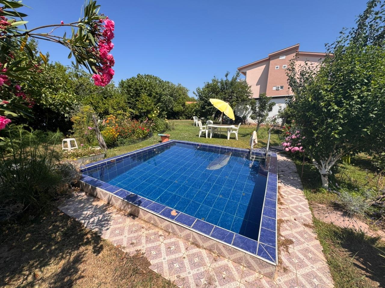 Charming blue-tiled pool in lush Ulcinj garden, perfect for relaxation. Prime Montenegro real estate by ekosphere doo&mdash;ideal investment.