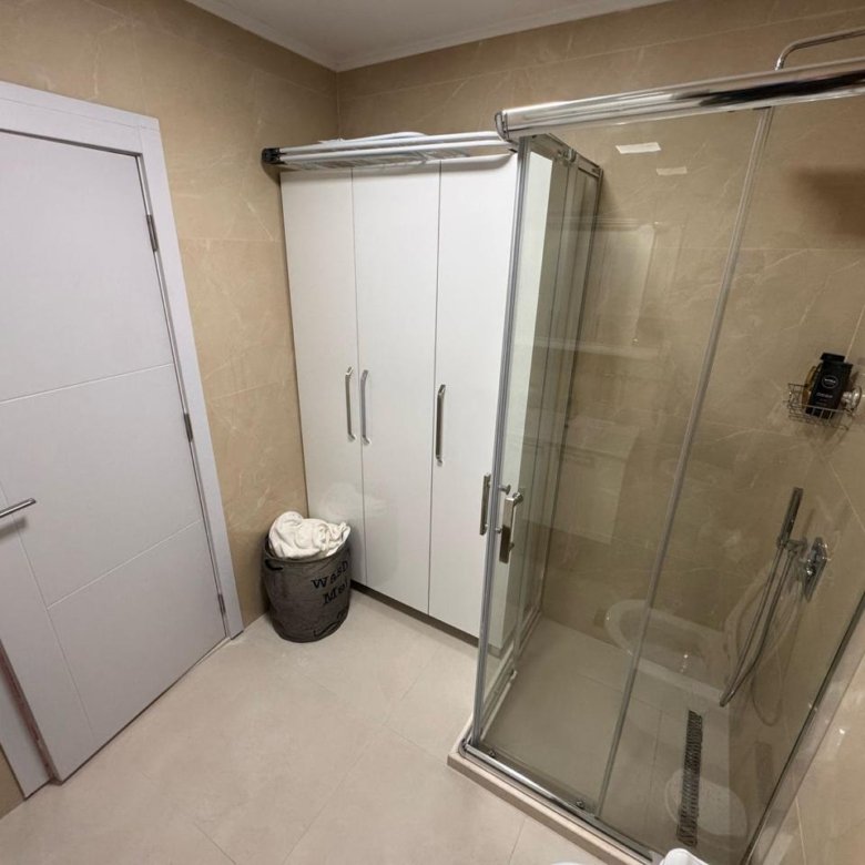 Elegant modern bathroom in Ulcinj, with beige tiles, glass shower, and storage; a premium investment by immorenta.me/Ekosphere doo.