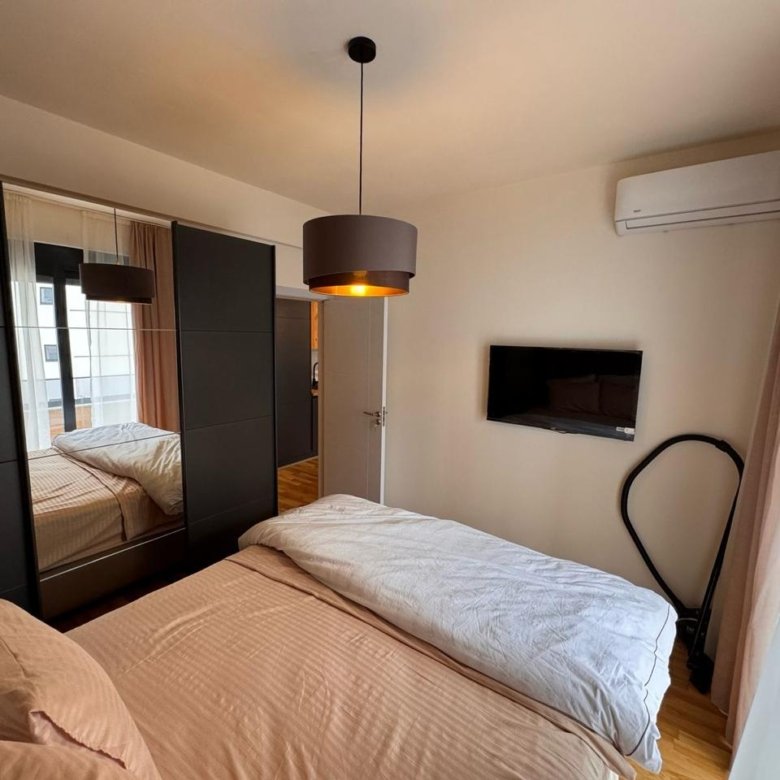 Modern Ulcinj bedroom: beige bedding, black wardrobe, AC, TV. Prime investment via immorenta.me by ekosphere doo.