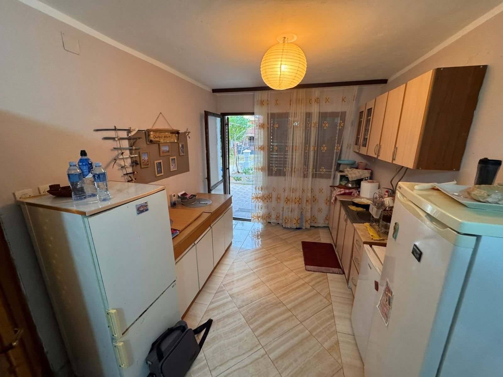 Modern compact kitchen in Ulcinj real estate, with white fridge, sleek cabinetry, bright lighting&mdash;offered by immorenta.me.