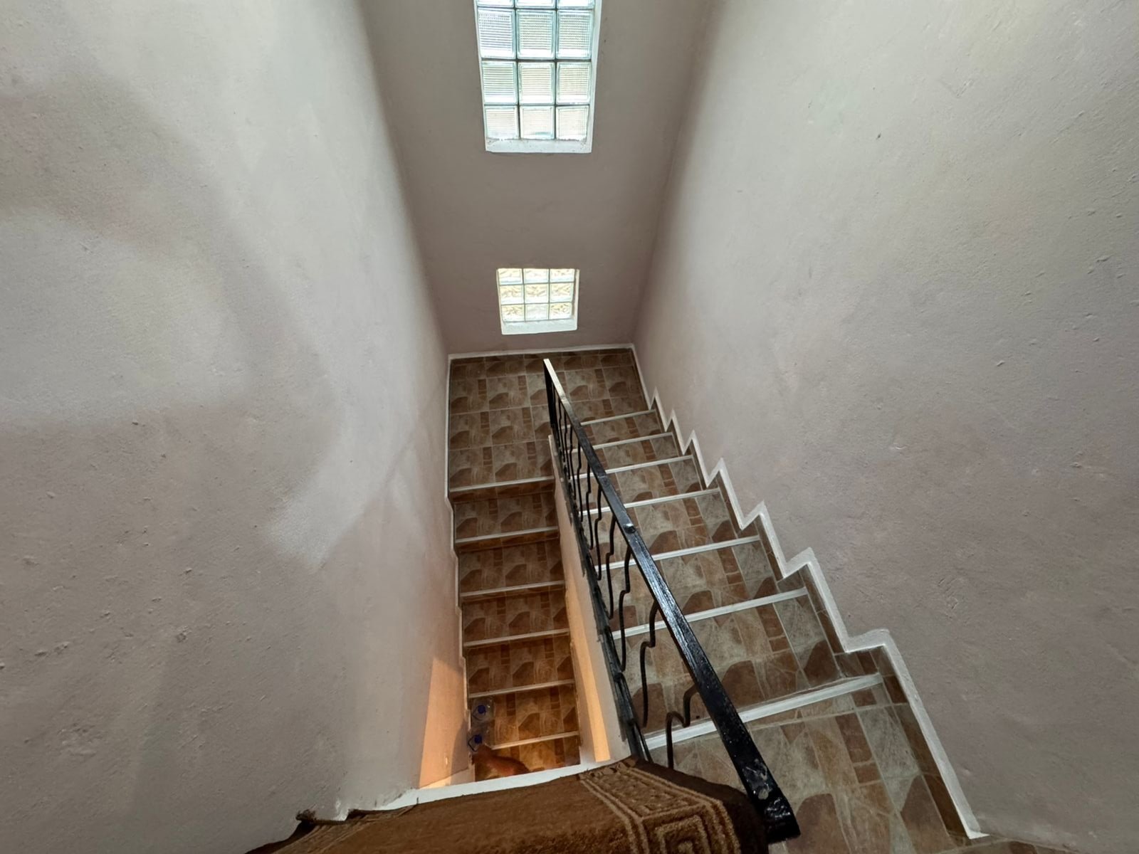 Modern staircase with brown tiles, black handrail, and skylights&mdash;bright, elegant Ulcinj real estate by ekosphere doo, immorenta.me.