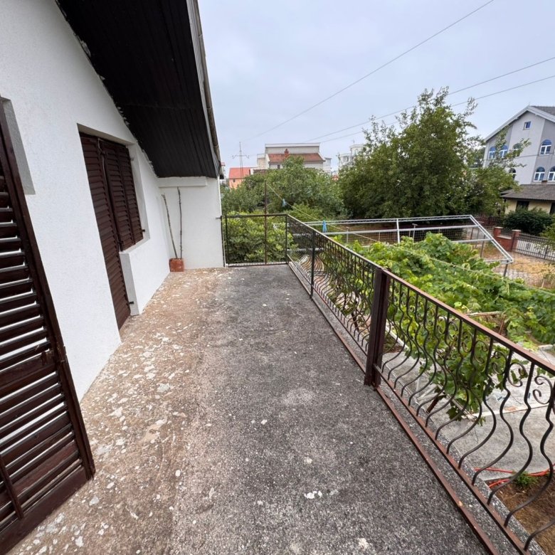 Modern concrete balcony with metal railing and lush garden views, prime Ulcinj property near amenities; listed on immorenta.me.