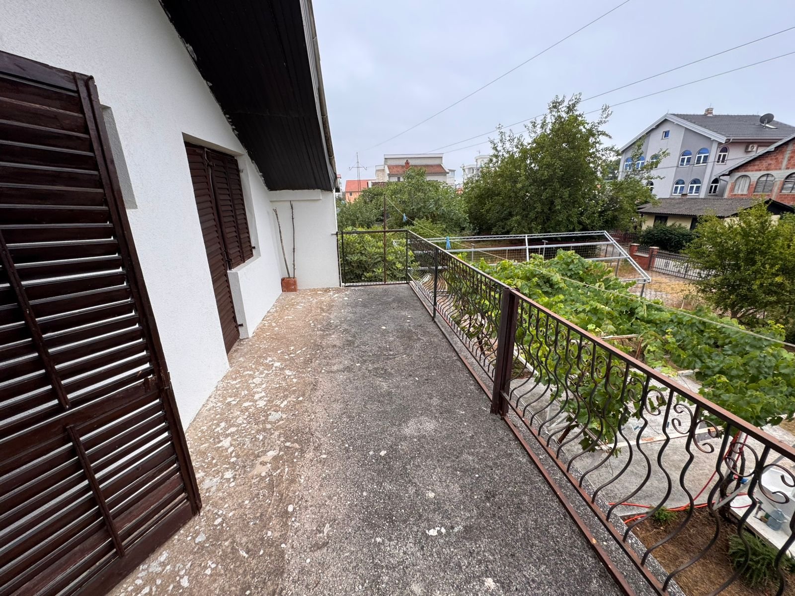 Modern concrete balcony with metal railing and lush garden views, prime Ulcinj property near amenities; listed on immorenta.me.