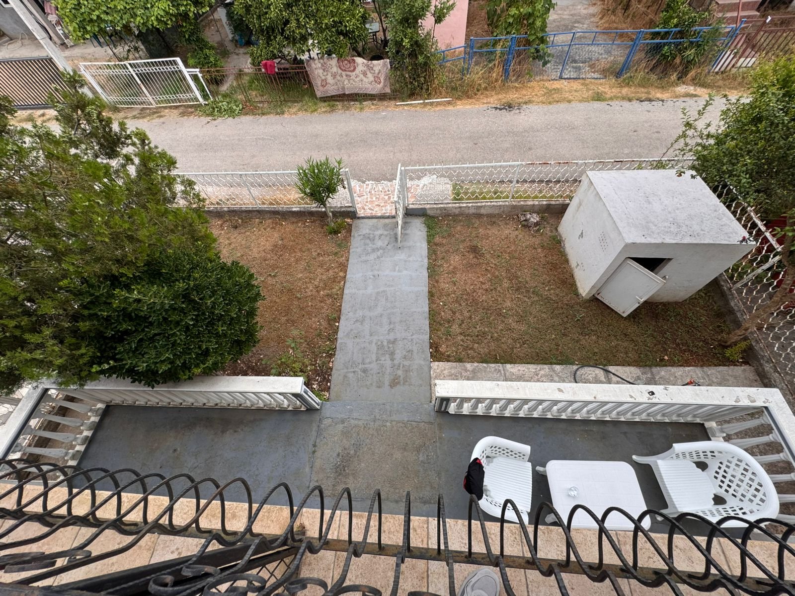 Upper balcony view in Ulcinj: private yard, stone path, white shed. Invest with immorenta.me, a project of Ekosphere doo.