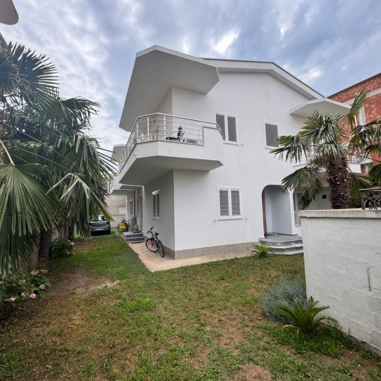 Elegant two-story white home in Ulcinj, Montenegro with balcony, palms, car and bike&mdash;prime real estate. Listed by ekosphere doo.