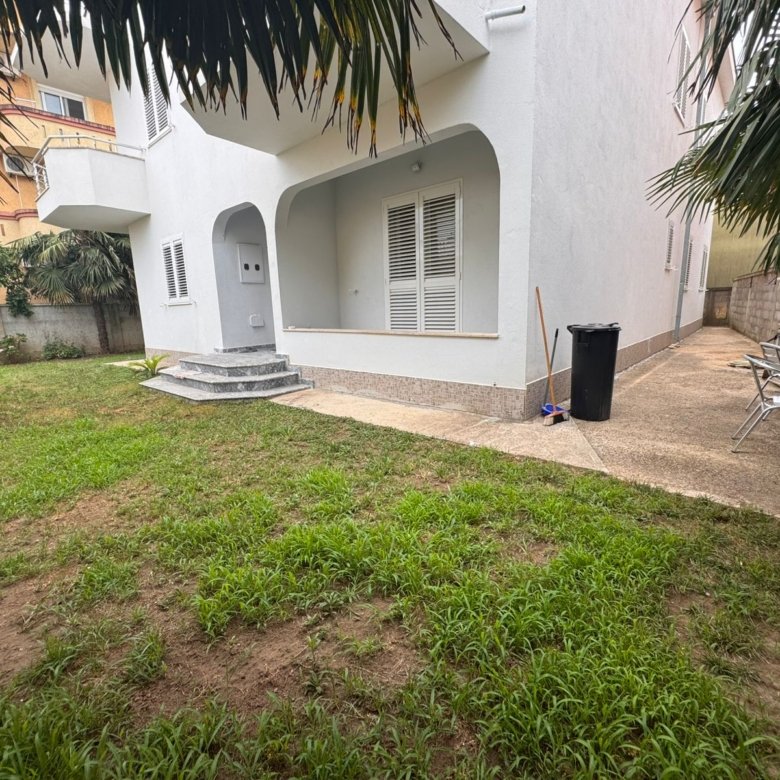 Modern white two-story home with porch, lush lawn, palm trees, and yard seating&mdash;prime Ulcinj real estate from Ekosphere on immorenta.me.