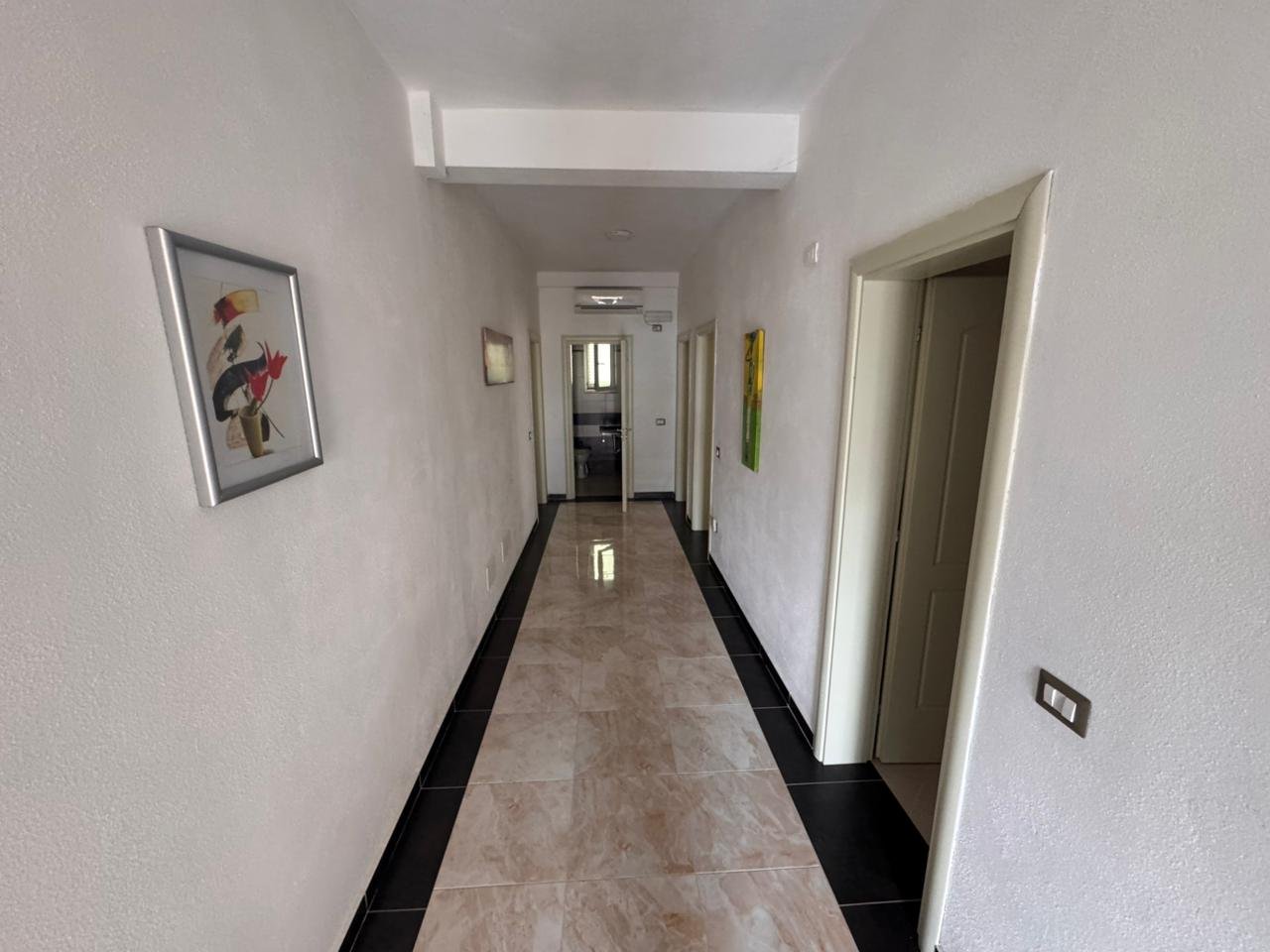 Elegant hallway with bright walls, glossy tiles, doors, and modern art&mdash;ideal Ulcinj investment. Listed by immorenta.me of Ekosphere doo.