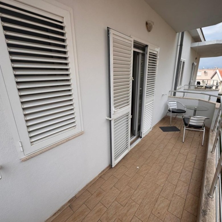 Ulcinj property for sale: tiled balcony, glass table, striped chairs, palm views. Ideal Montenegro real estate from ekosphere doo.