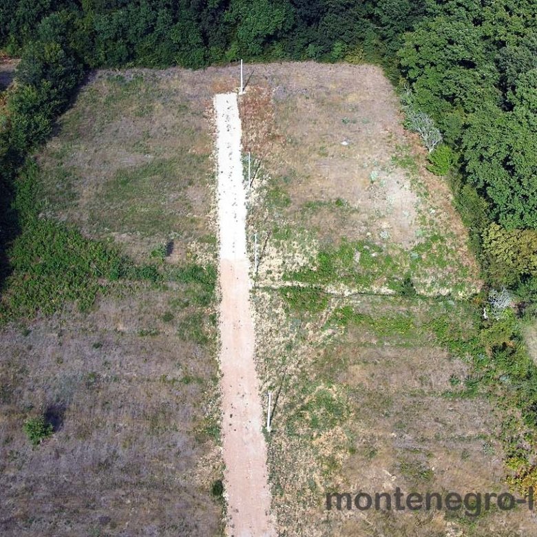 Aerial view of Ulcinj fields ideal for property investment, with road access and lush trees. Montenegro-listings.me by ekosphere doo.