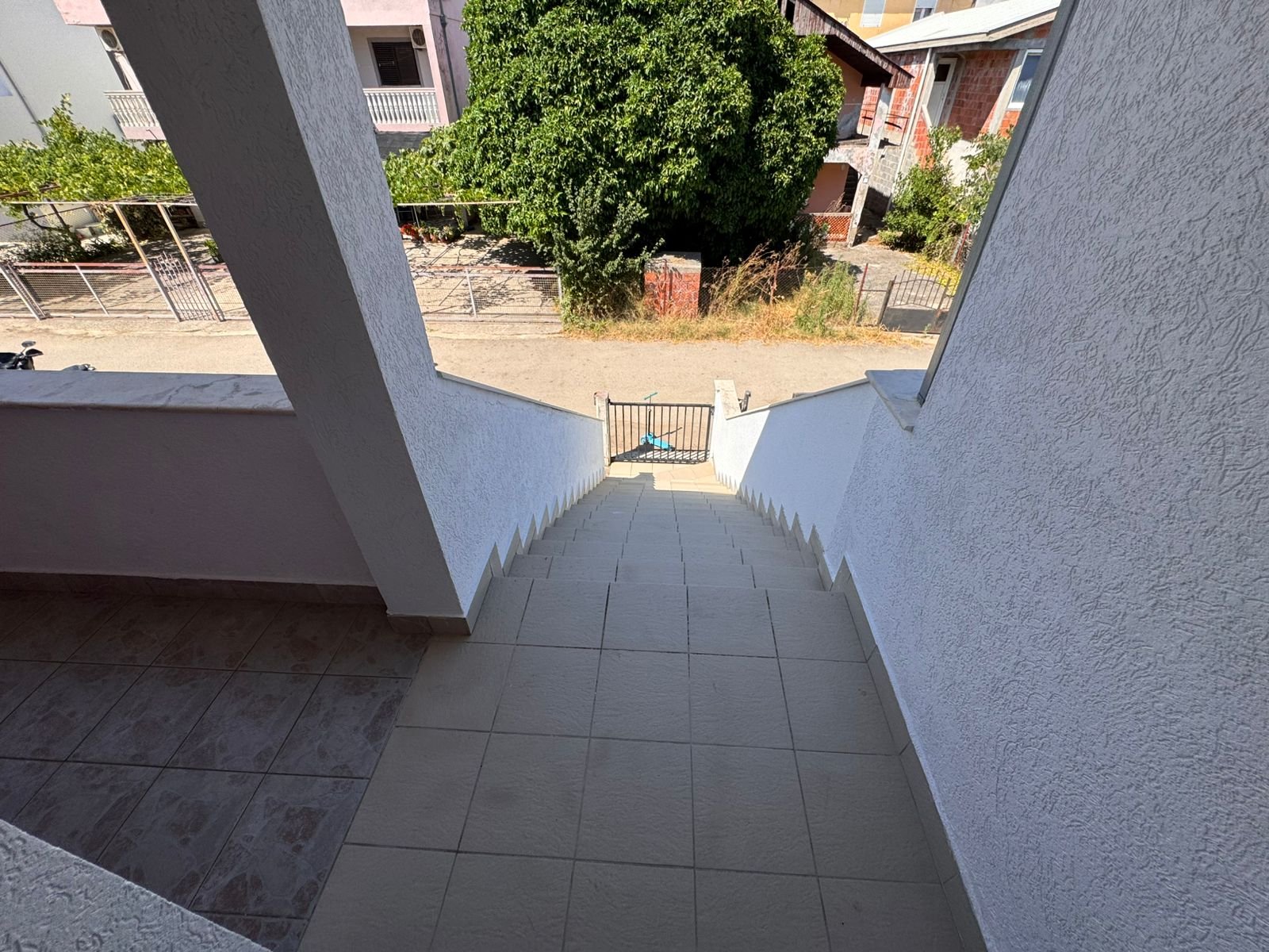 Stunning Ulcinj property: tiled stairs, secure gate, tree-lined street & white homes. A prime real estate investment via immorenta.me by ekosphere doo.