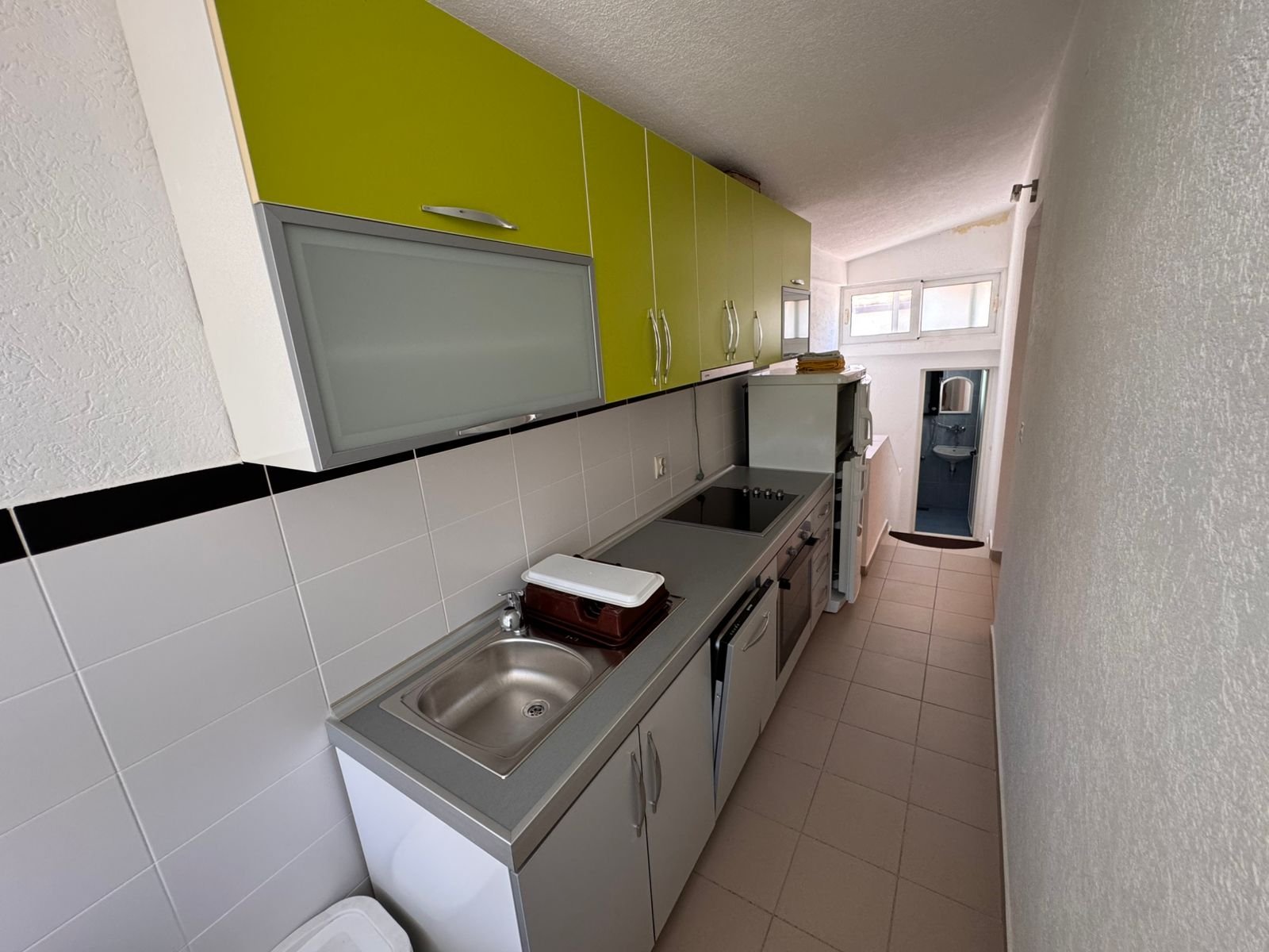 Modern galley kitchen in Ulcinj property: stylish white/green cabinets, stainless appliances, laundry zone&acirc;invest at immorenta.me by ekosphere doo.