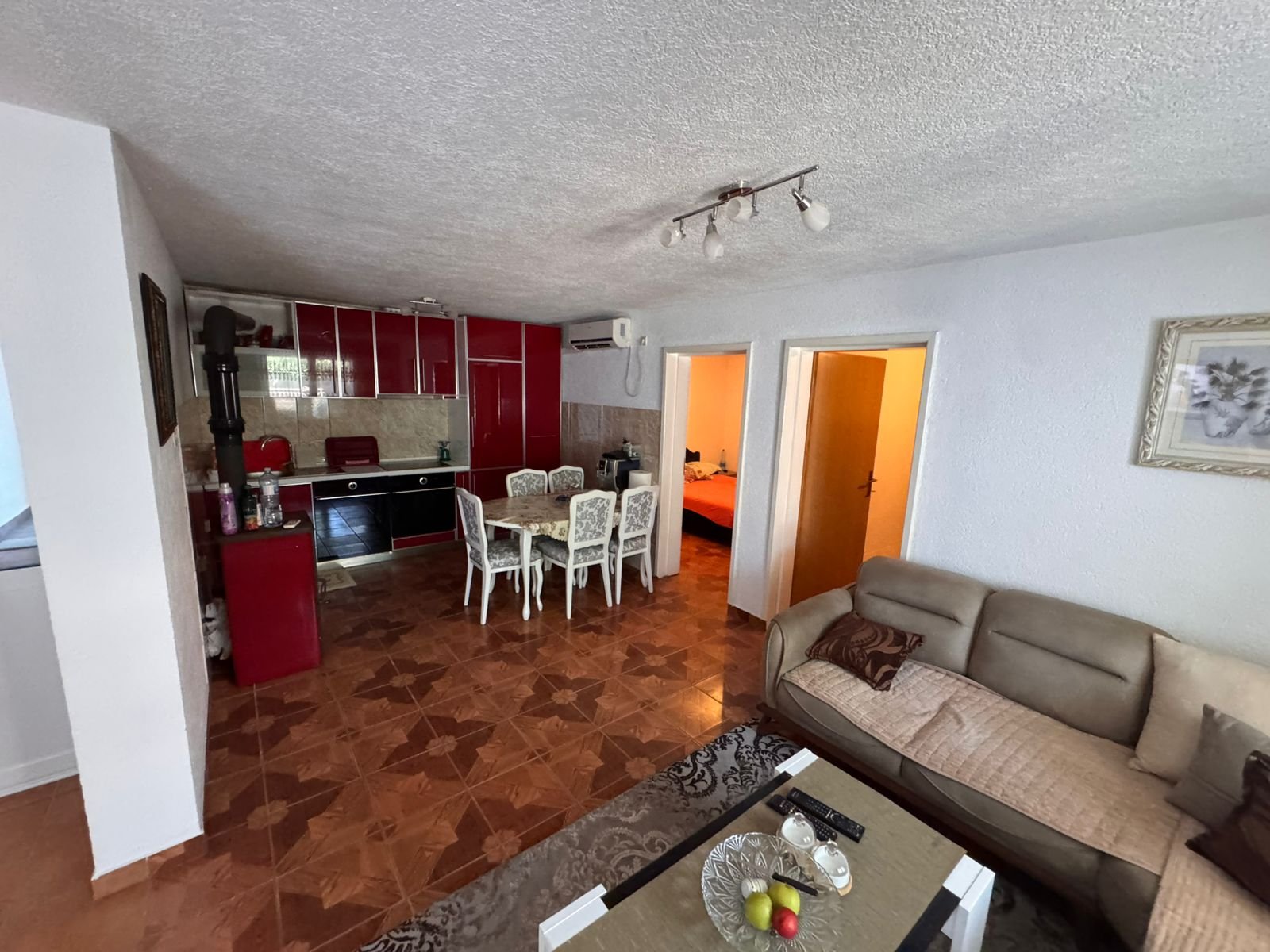 Modern Ulcinj apartment: beige sofa, stylish coffee table, open-plan kitchen with red cabinets, spacious dining&acirc;exclusive on immorenta.me by ekosphere doo.