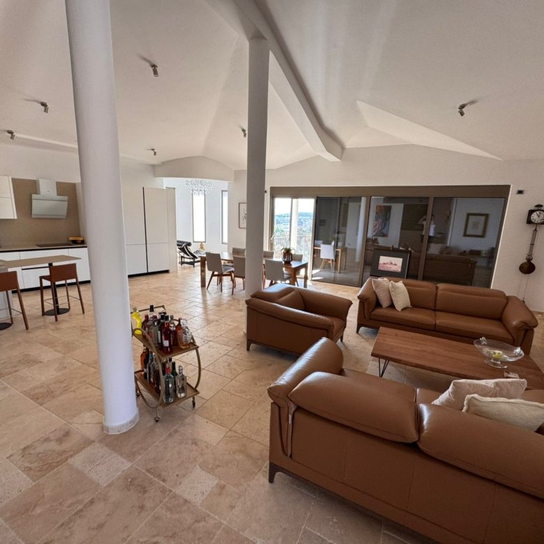 Elegant modern living room in Ulcinj, Montenegro&mdash;tan leather sofas, open kitchen, large windows&mdash;listed by immorenta.me.