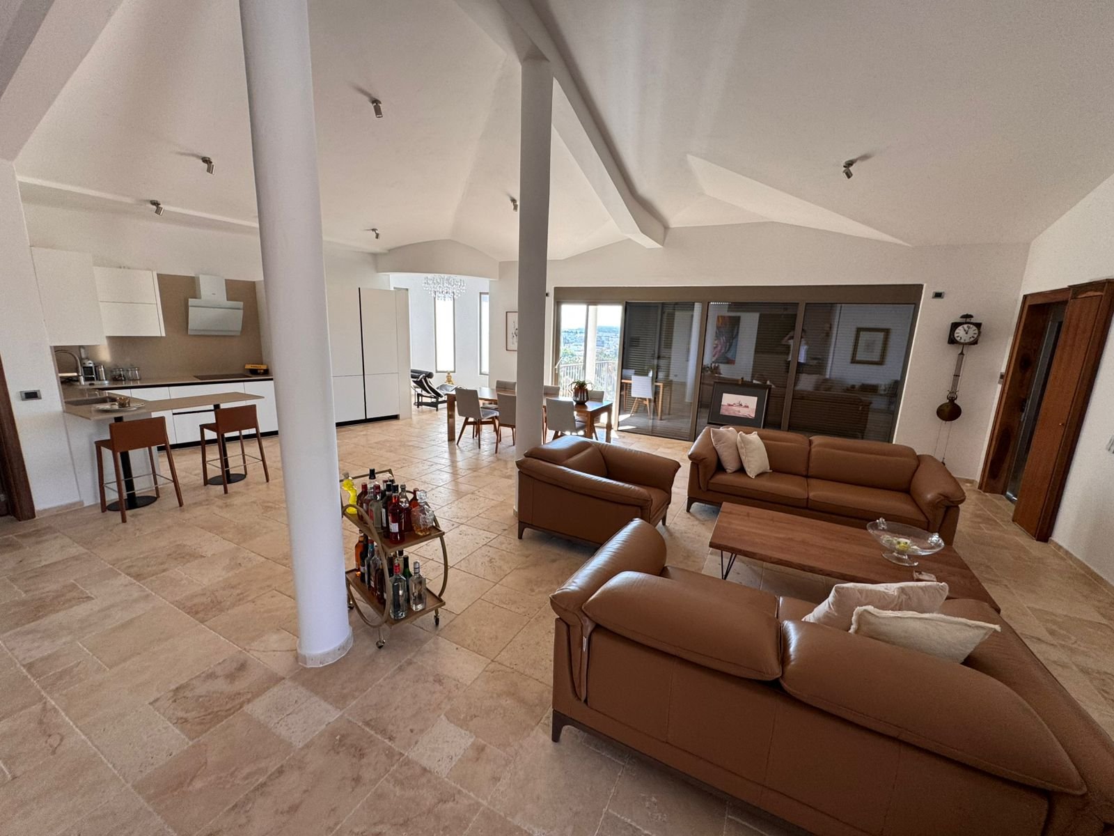 Elegant modern living room in Ulcinj, Montenegro&mdash;tan leather sofas, open kitchen, large windows&mdash;listed by immorenta.me.