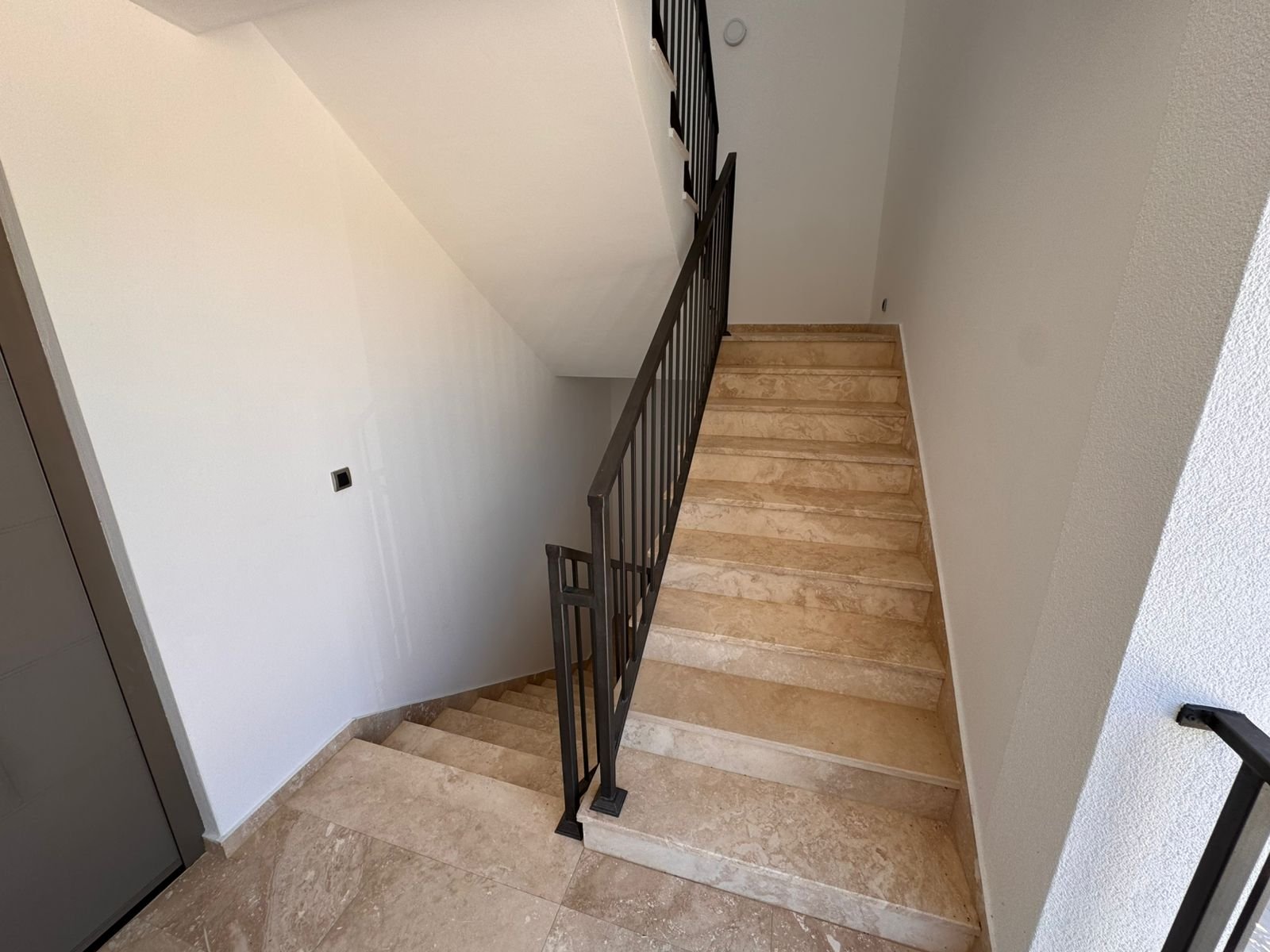 Elegant staircase with beige marble steps and black railings, featured in luxury Ulcinj properties at immorenta.me by Ekosphere.