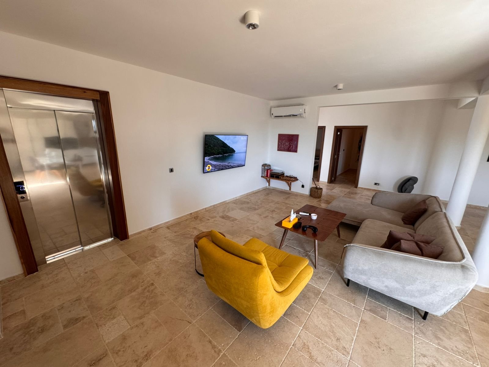 Stylish modern living room in Ulcinj with beige tiles, elegant sofa, TV, and elevator&mdash;ideal Montenegro investment via ekosphere doo.