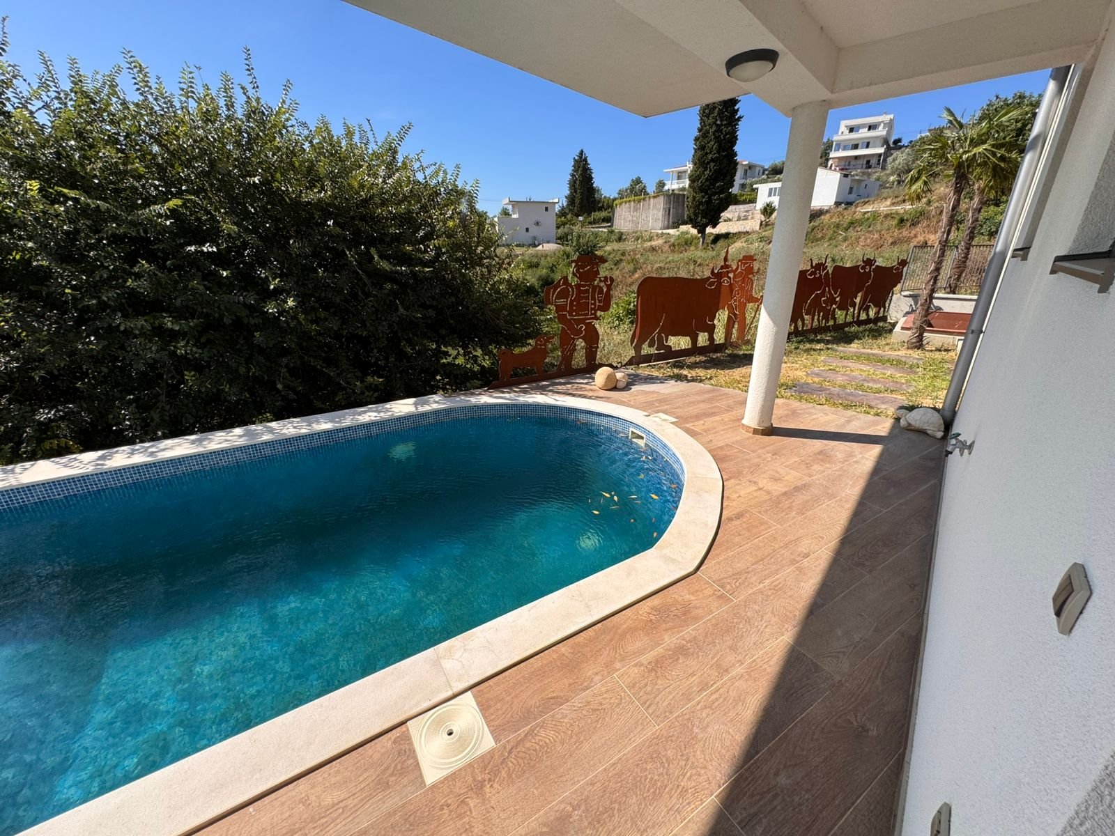 Modern curved pool with pristine blue water, stylish tile border, and unique metal fencing&mdash;prime Ulcinj real estate by ekosphere doo.