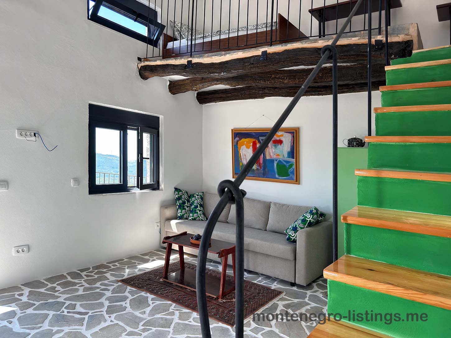 Ulcinj living room with gray sofa, vibrant cushions, wood table, green stairs. Exclusive Ekosphere property on immorenta.me.