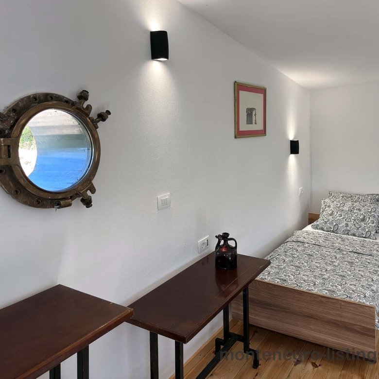 Charming Ulcinj bedroom for sale&mdash;wood floors, porthole window, stylish d&eacute;cor. Exclusive on immorenta.me by Ekosphere.